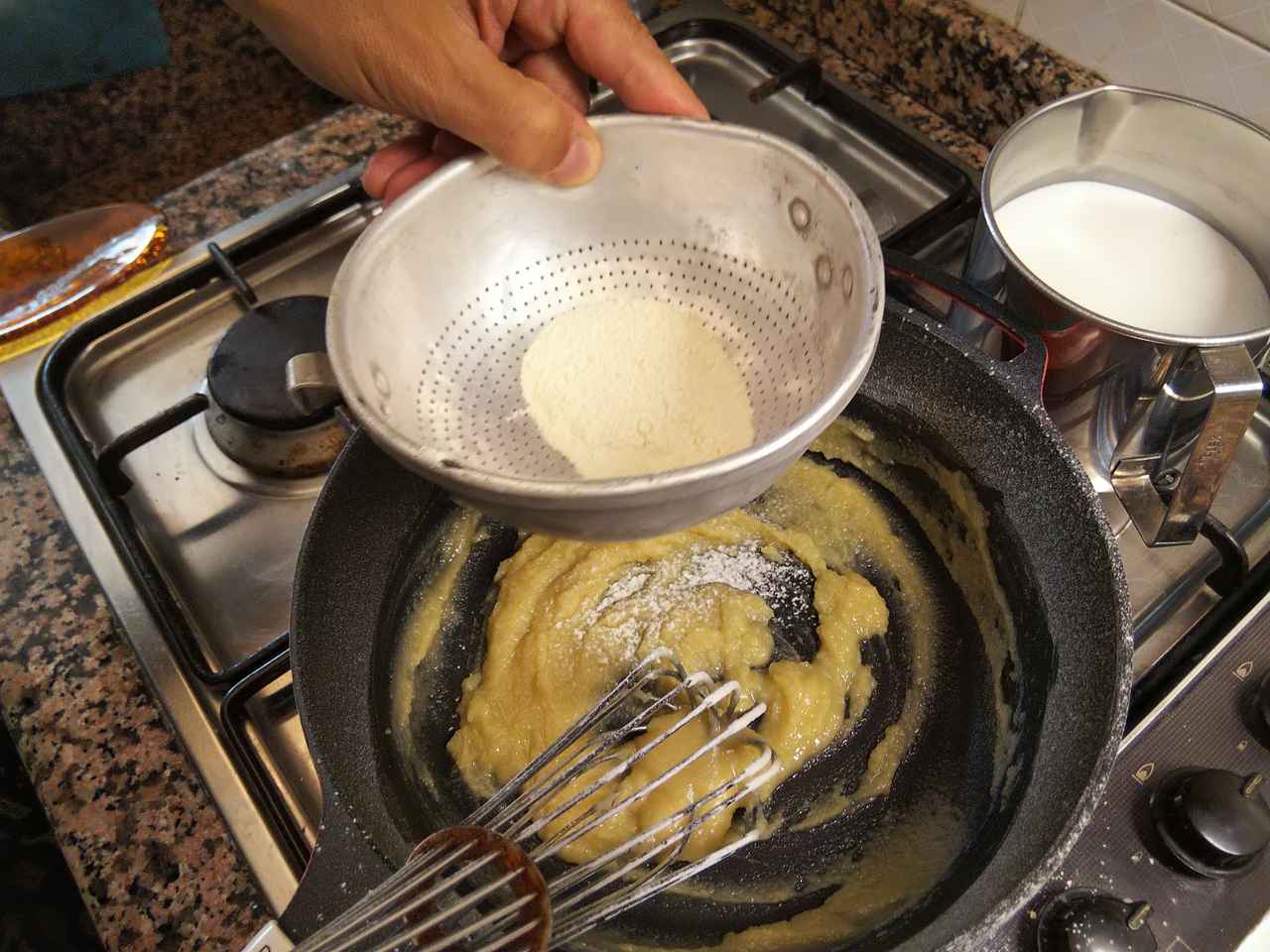 画像: 手順４．溶かしたバターに小麦粉を振るい入れながら泡だて器で混ぜる （筆者撮影）
